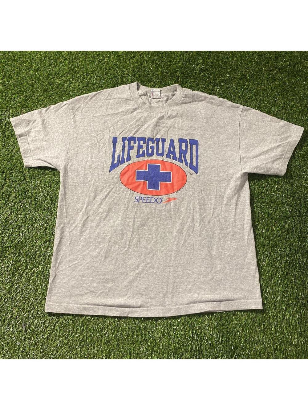 Vintage 90โs Speedo lifeguard tee with blue text and red oval with blue cross